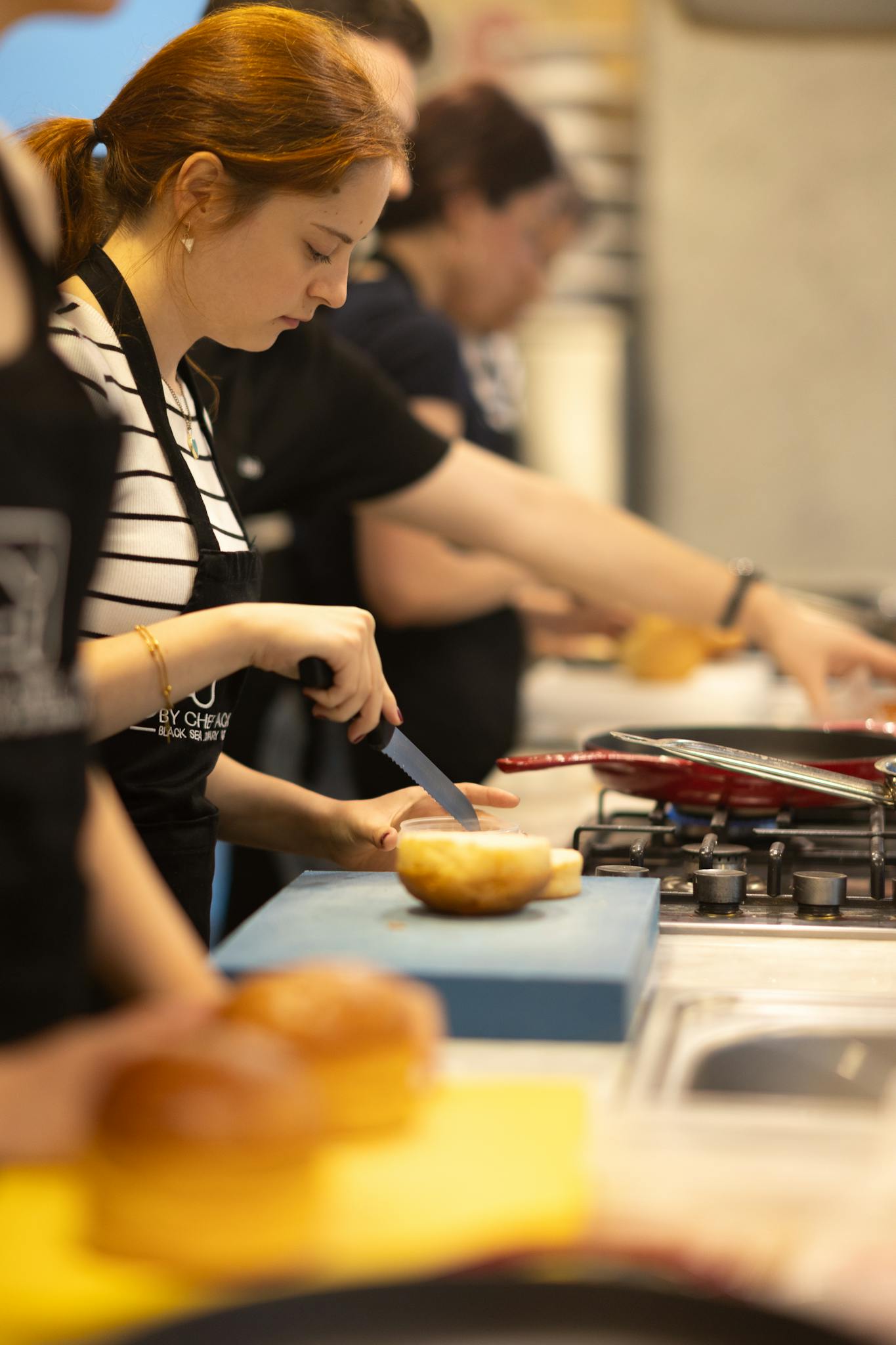 Focused woman slicing bread during a cooking class in Samsun, Türkiye.