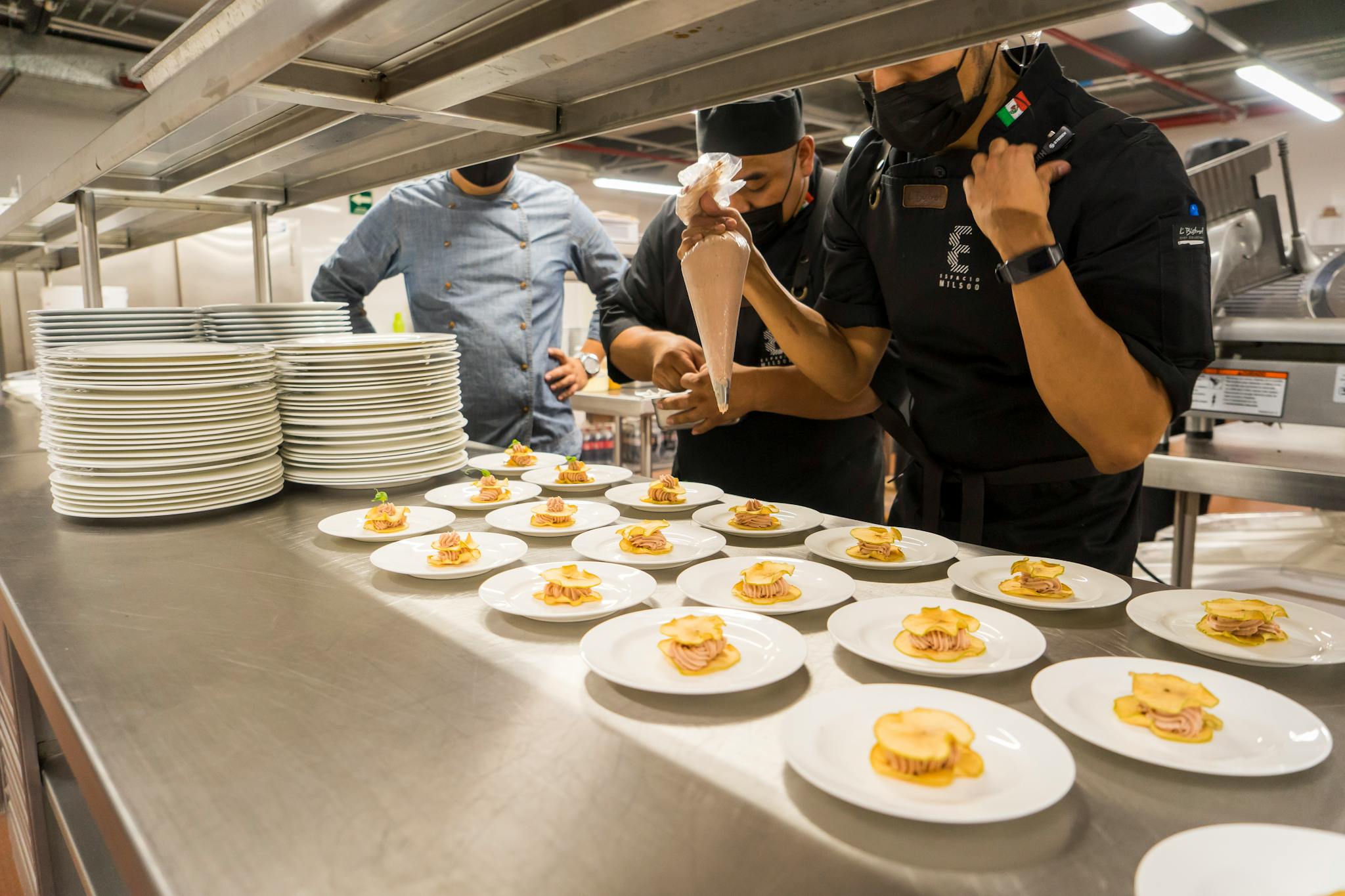 Team of chefs creatively plating gourmet appetizers in a commercial kitchen.